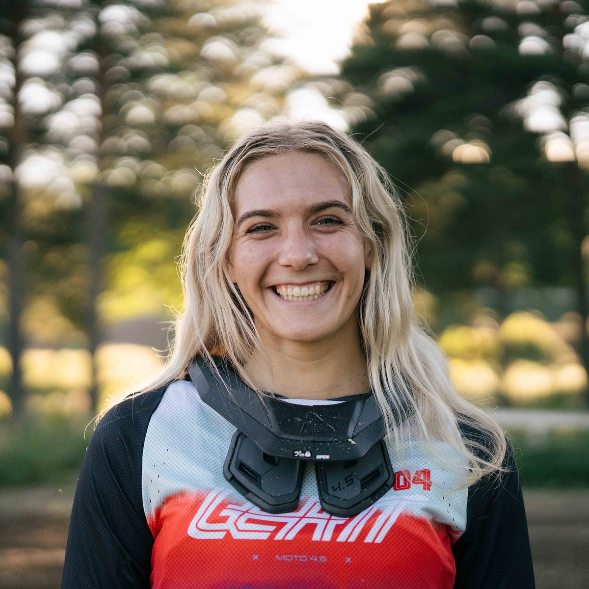 Sara Andersen sitting on a dirt bike with trees and clear sky in the background